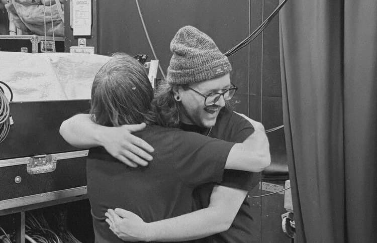 Two people hugging backstage next to road cases